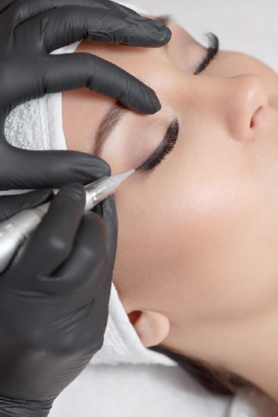 Cosmetologist making permanent makeup, close up. Tattooist making permanent make-up. Attractive lady getting facial care and tattoo. Permanent make-up tattoo at beauty salon